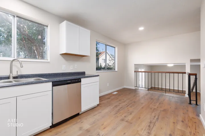 Modern kitchen space featuring white shaker cabinetry, a stainless steel dishwasher, and a dual basin sink with a brushed nickel faucet