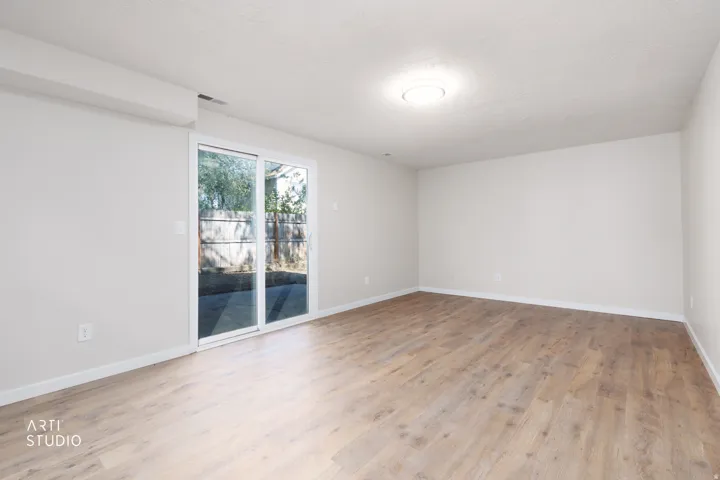 Spacious room featuring wood-finish flooring, light-toned walls, and a ceiling-mounted light fixture