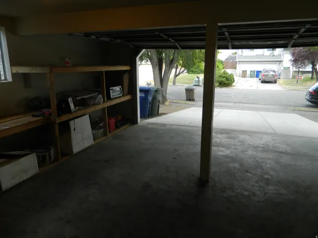 Attached garage with concrete flooring, integrated shelving, and a window