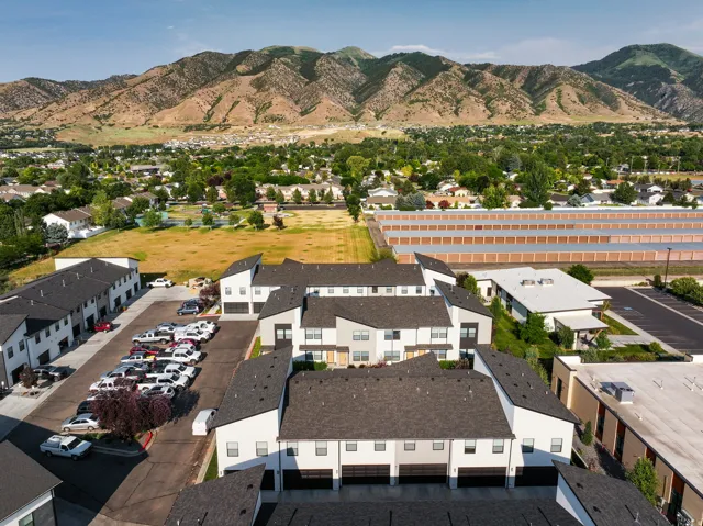 Modern townhome development featuring white and gray exteriors, dark shingle roofing, and integrated garage doors