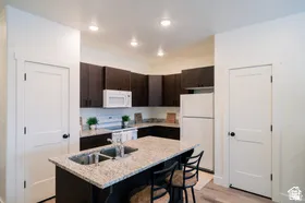 Kitchen featuring an island with a double basin sink, light-toned countertop, and seating for two