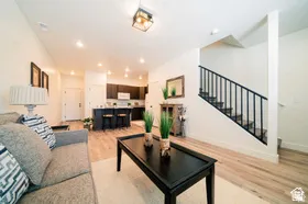 Bright open-concept living area featuring wood-finish flooring, recessed lighting, and a modern staircase with dark metal railings