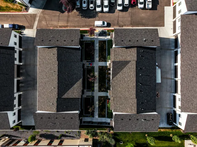 Contemporary multi-unit residential complex featuring dark shingle roofs, white exterior facades, and multiple parking areas