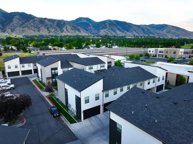 Modern townhome exteriors featuring white and dark gray facades, dark shingle roofing, and integrated garages