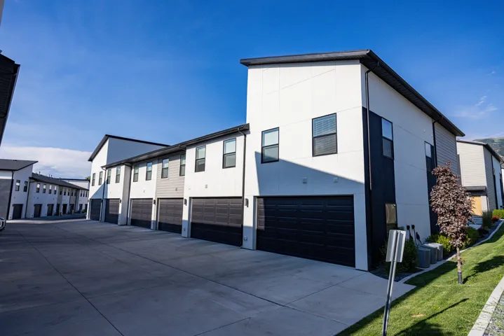 Modern townhome-style residences featuring two-car garages, a concrete driveway, and contrasting exterior siding