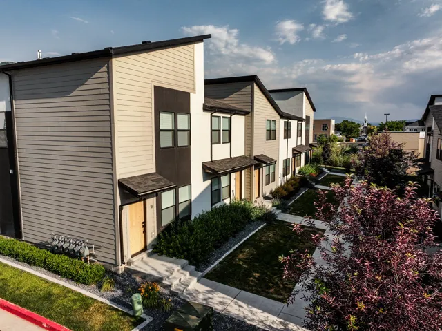 Contemporary townhome exterior featuring multi-toned siding, black window frames, and covered entryways