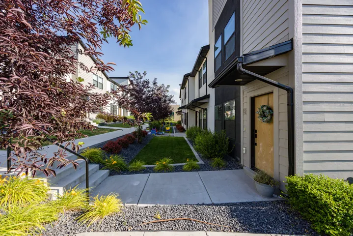 Modern townhome exterior featuring light gray horizontal siding and dark accent panels
