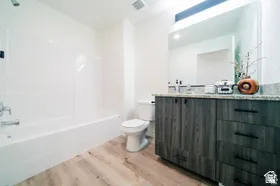 Bathroom featuring a wood-finish vanity with dark hardware, a light-toned countertop, and an integrated rectangular sink