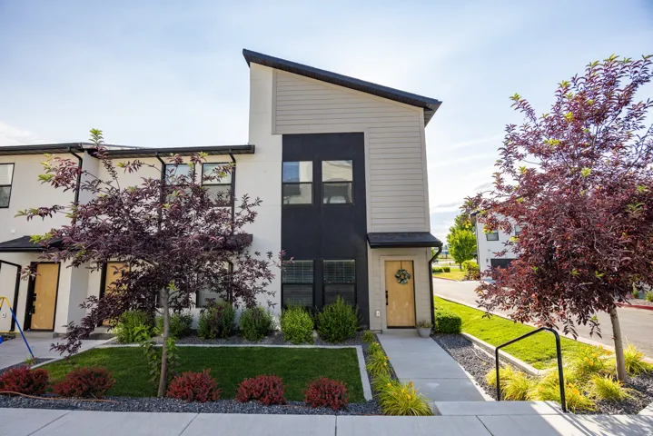 Modern exterior with contrasting light and dark siding, a natural wood-finish front door, and a striking asymmetrical roofline