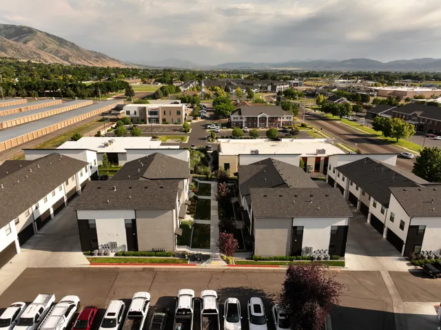 Modern multi-family complex featuring pitched and flat roofs, private garages, and landscaped courtyards