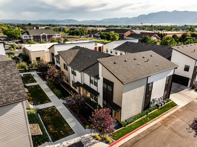 Contemporary townhome architecture featuring varied exterior siding, dark shingles, and a paved street