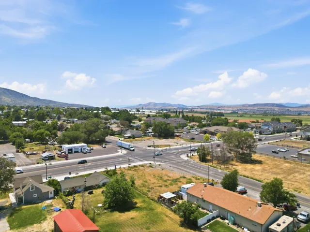 Expansive aerial showing a community with a prominent intersection, commercial structures, and residential properties