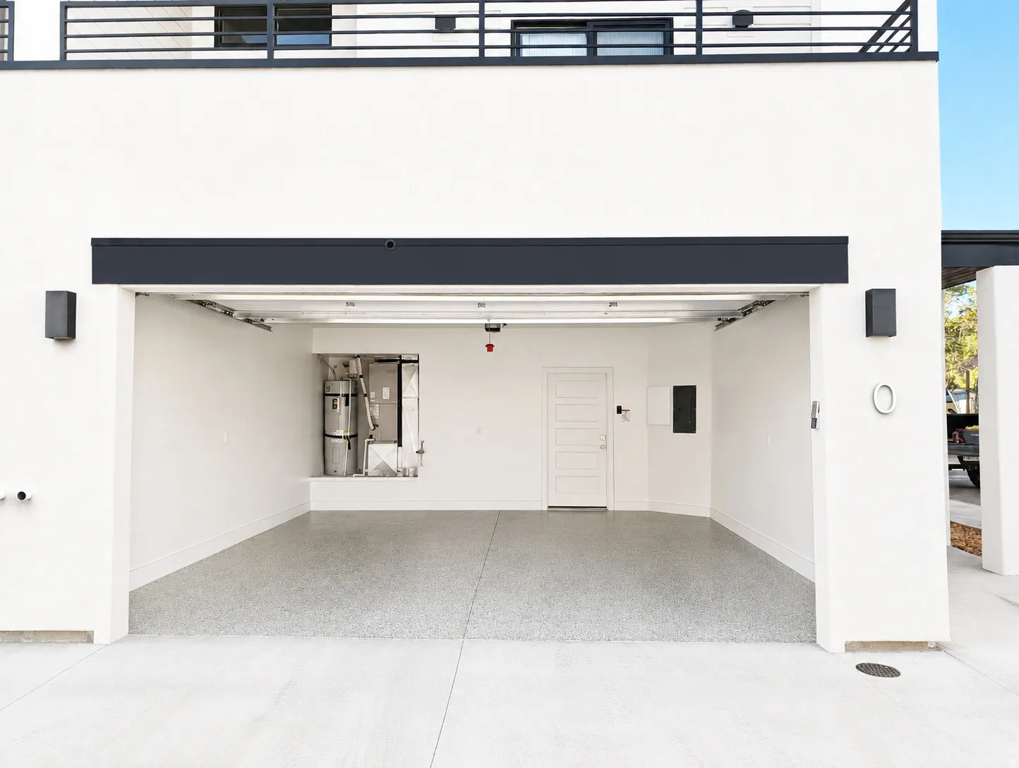 Two-car garage featuring an epoxy-coated concrete floor, white interior walls, and a panel door for interior access