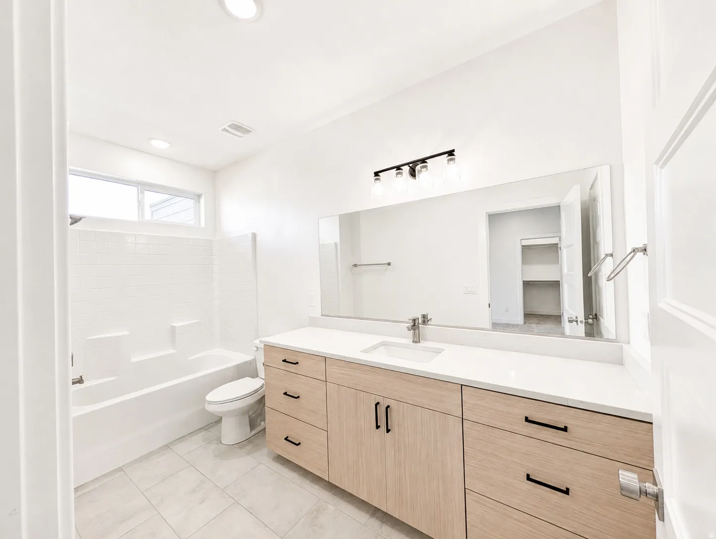 Bathroom featuring a modern vanity with light wood-finish cabinetry, a large integrated sink, and a white countertop