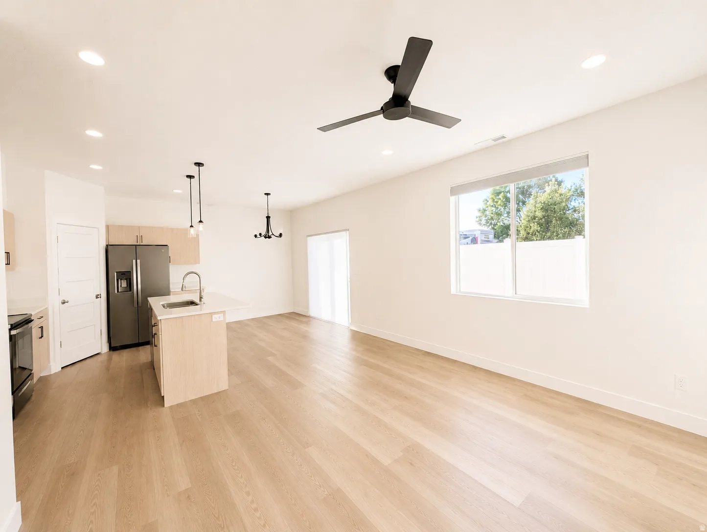 Open-concept living area featuring light wood-finish flooring, recessed lighting, and a contemporary ceiling fan