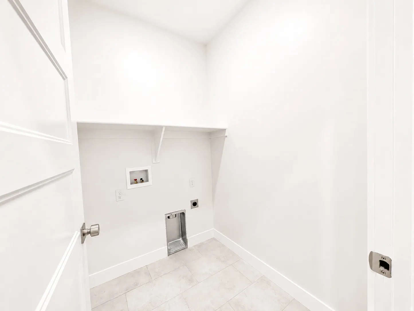 Laundry area featuring tile flooring, white walls, built-in shelving, and hookups for appliances