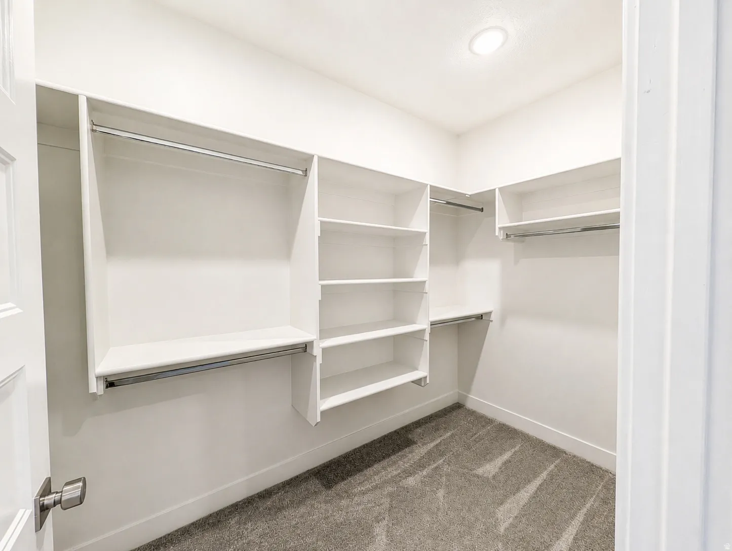 Walk-in closet featuring built-in white shelving, multiple hanging rods, recessed ceiling lighting, and carpet flooring