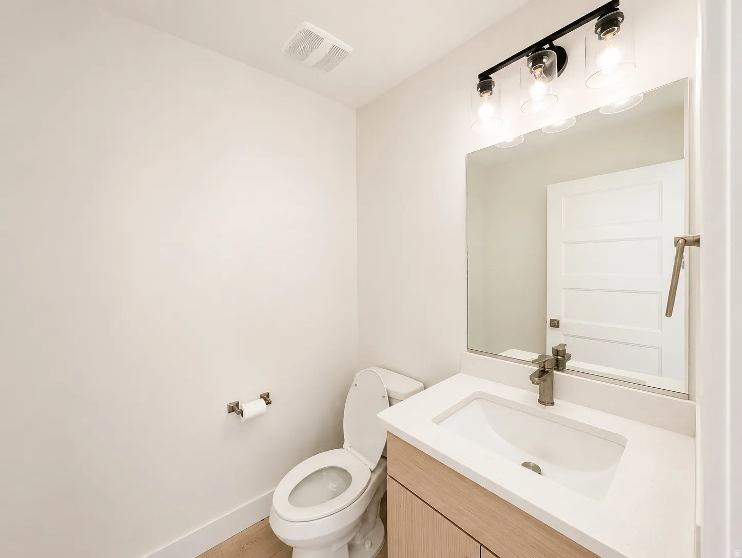 Bathroom featuring a wood-finish vanity with a white countertop and integrated sink