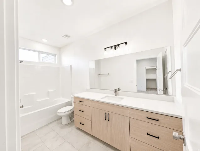 Bathroom featuring a modern vanity with light wood-finish cabinetry, a large integrated sink, and a white countertop