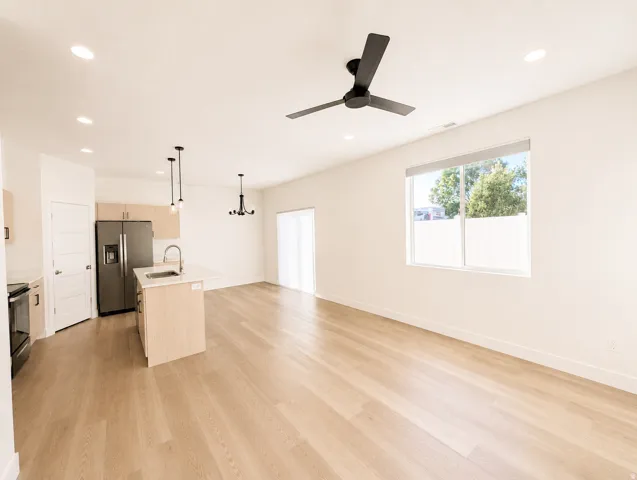 Open-concept living area featuring light wood-finish flooring, recessed lighting, and a contemporary ceiling fan