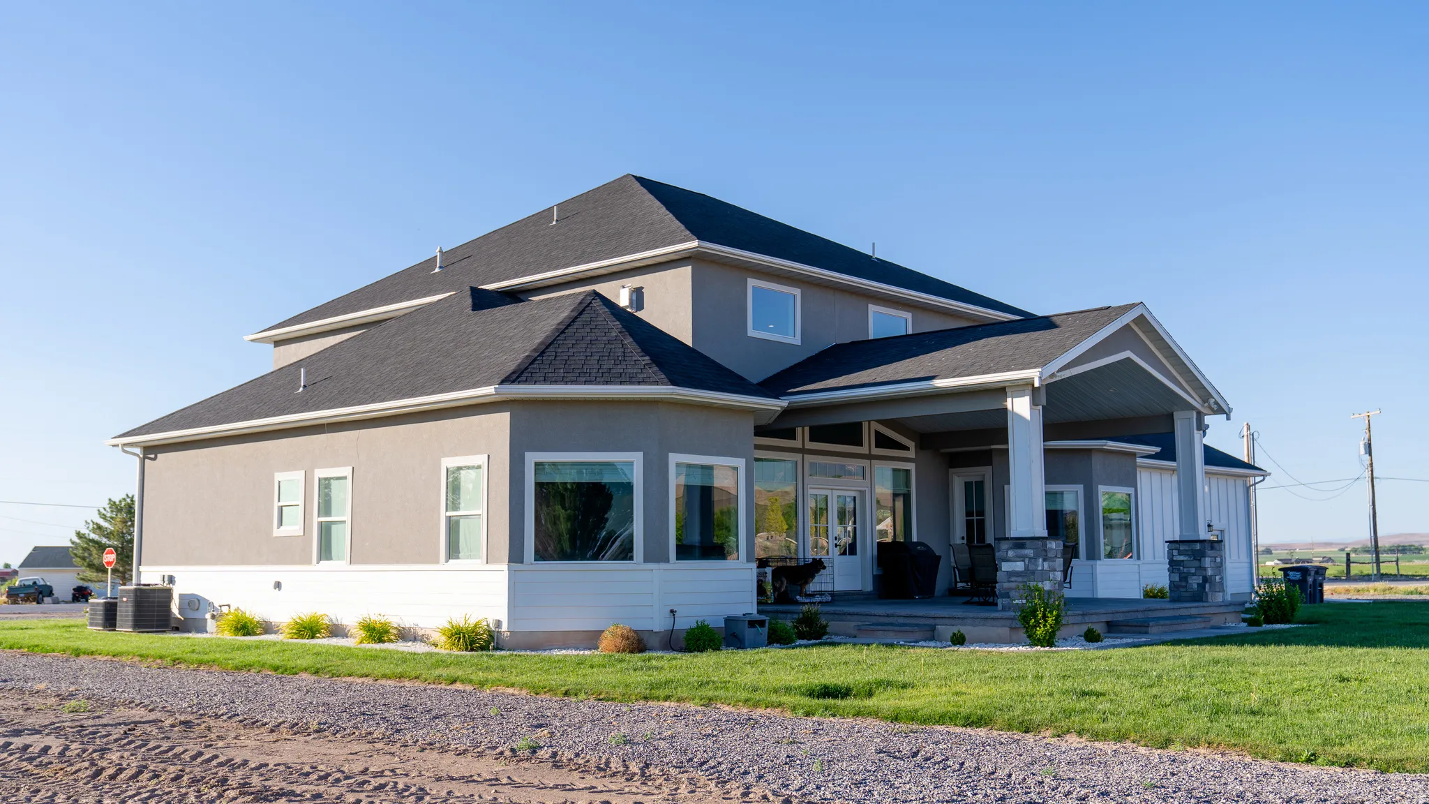 Contemporary two-story residence featuring a stucco exterior with a contrasting white lower band and a dark shingle roof