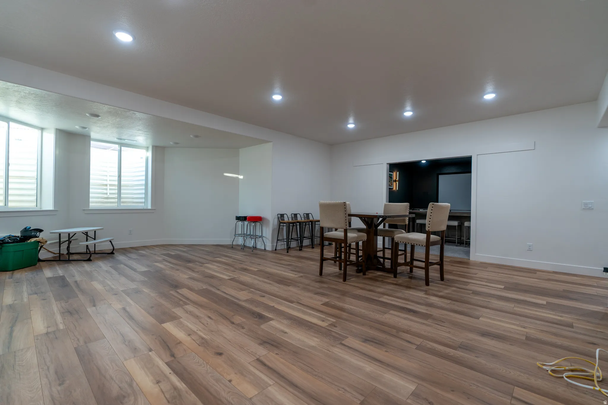 Spacious lower-level area featuring wood-finish flooring, recessed lighting, and multiple egress windows with horizontal blinds