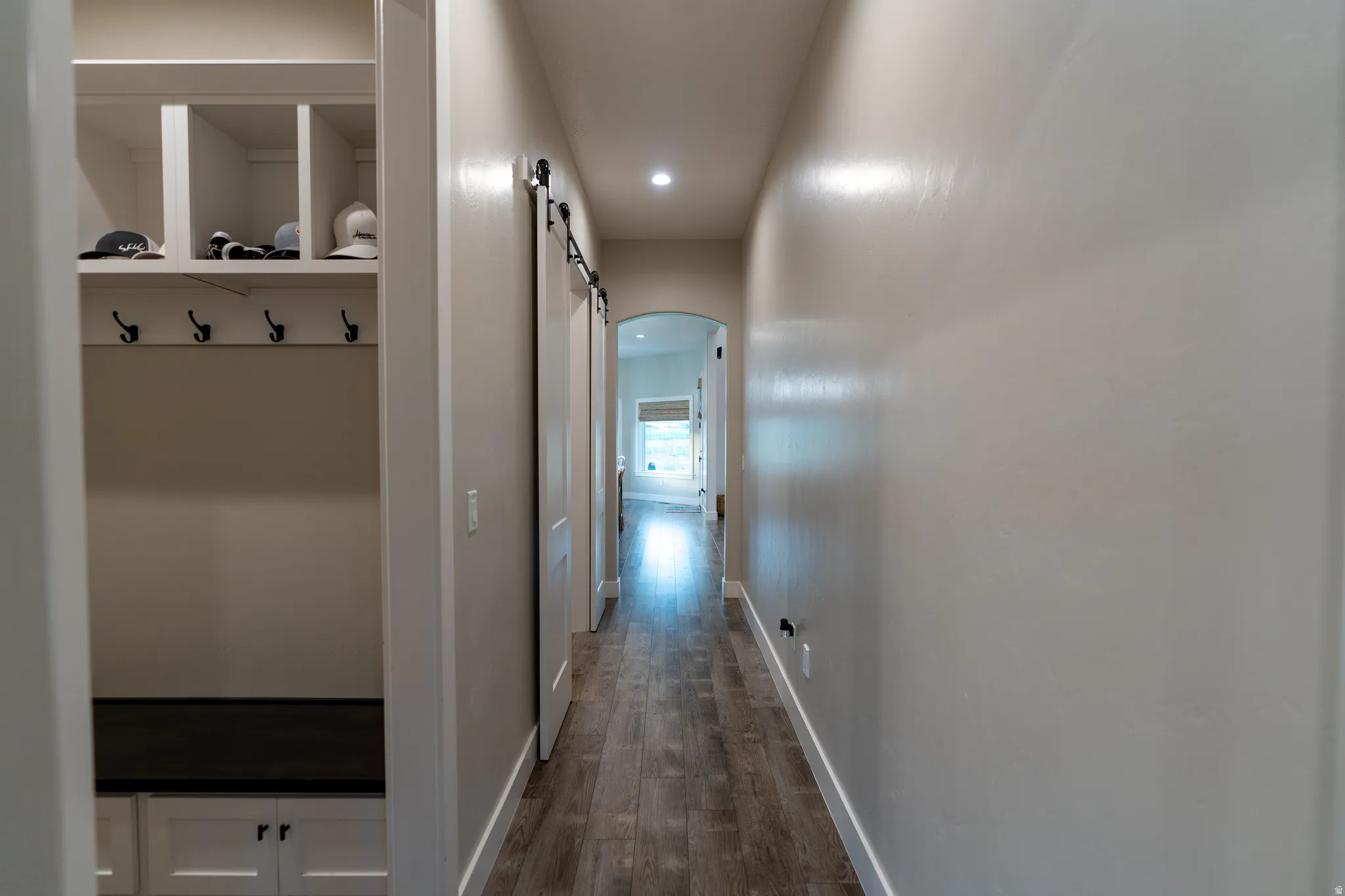 Hallway featuring built-in white cabinetry with a dark-finish bench, integrated storage cubbies, and coat hooks