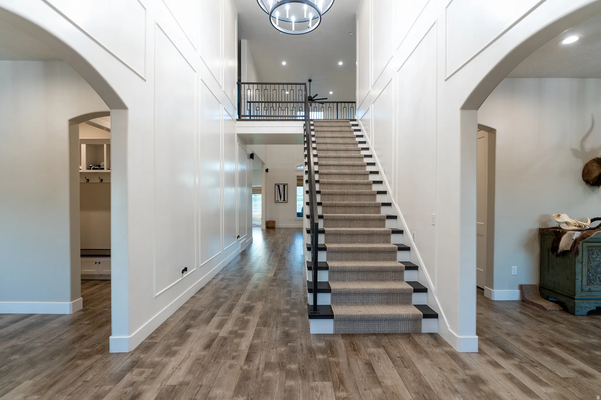 Two-story foyer featuring a grand staircase with carpeted treads and a wrought iron railing