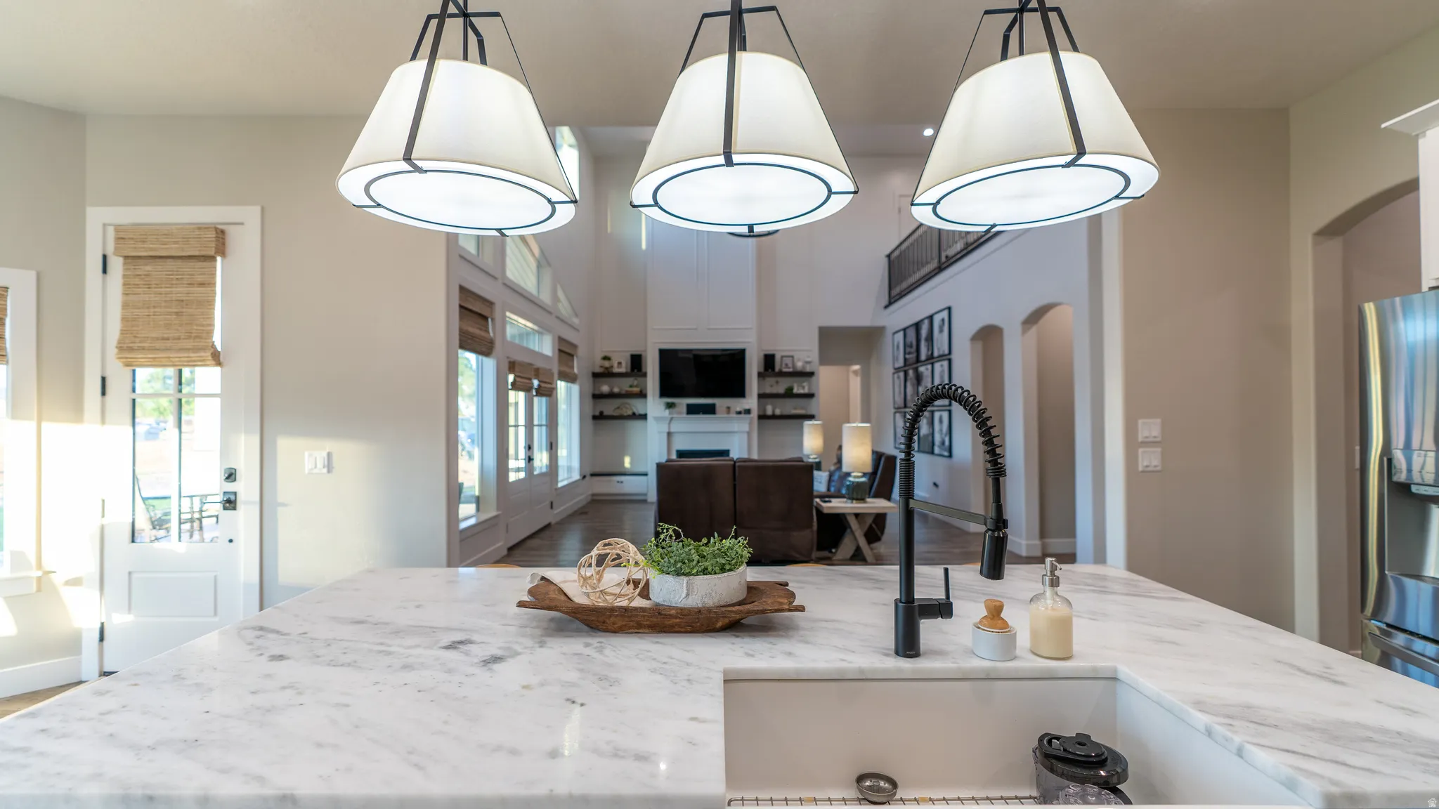 Spacious kitchen island featuring a white stone countertop, undermount sink, and a black gooseneck faucet