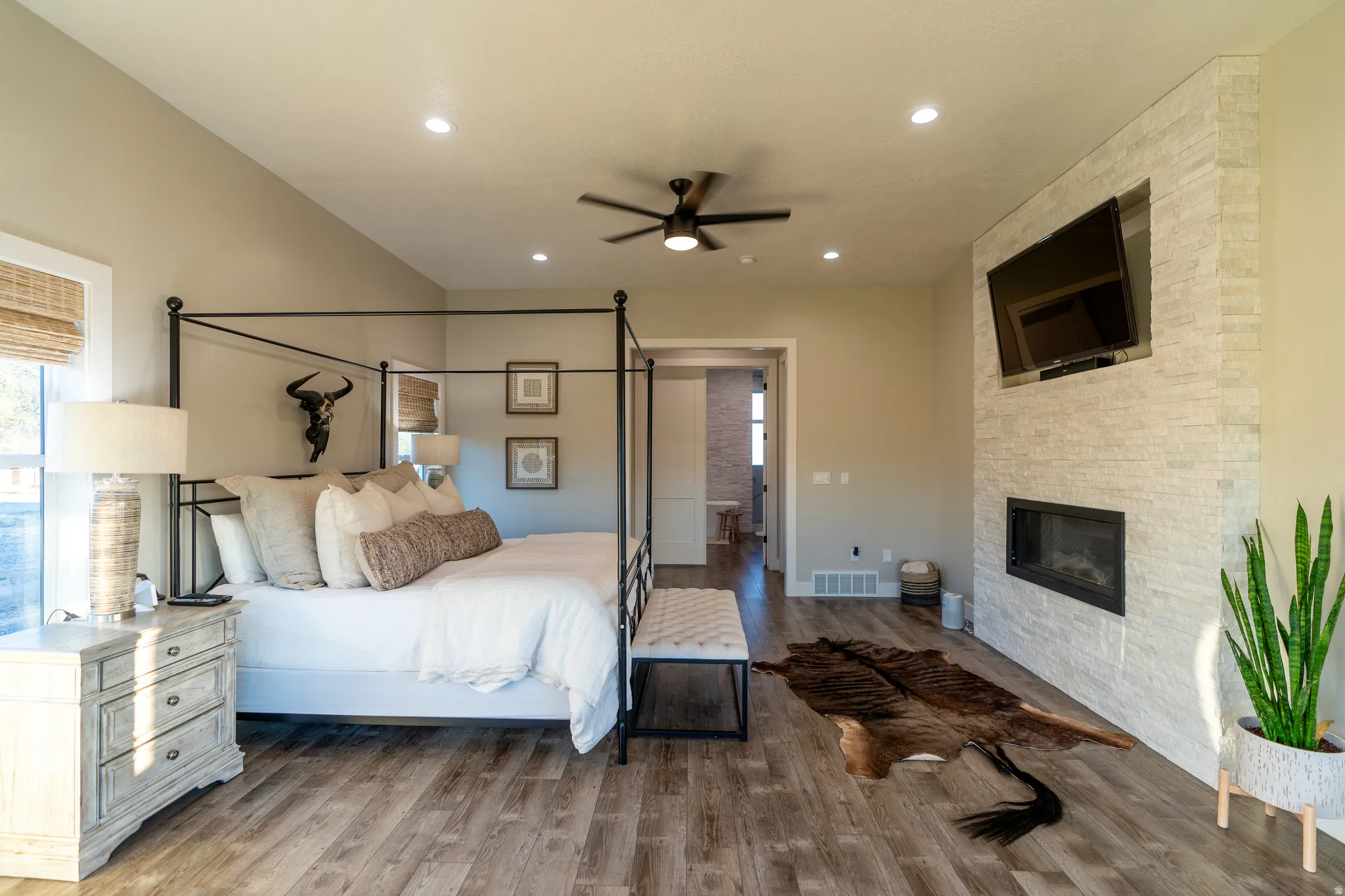 Spacious room featuring vaulted ceilings, wood-finish flooring, a contemporary fireplace with stacked stone surround, and recessed lighting