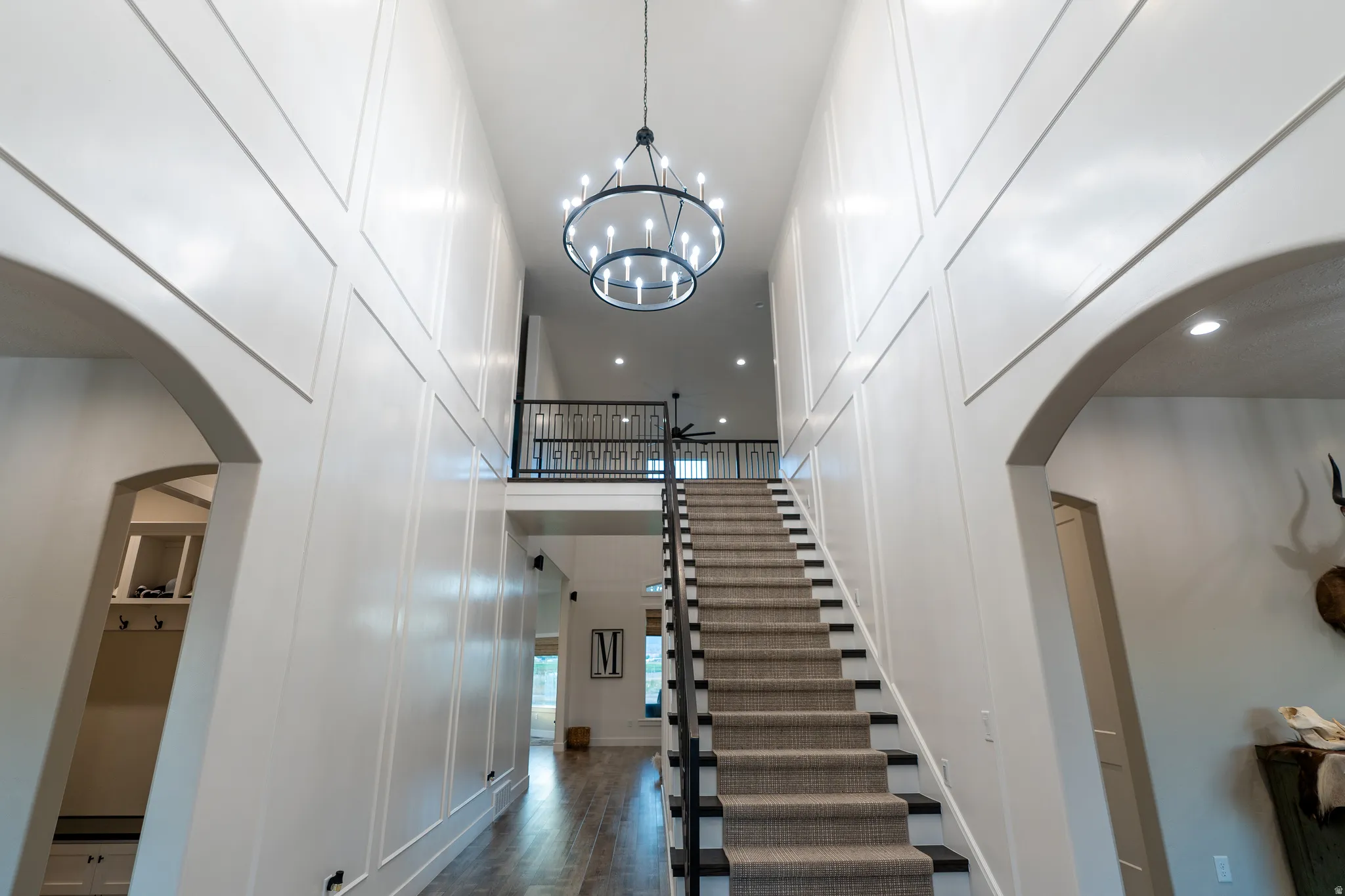 Two-story foyer featuring a grand staircase with carpeted treads and dark wood risers