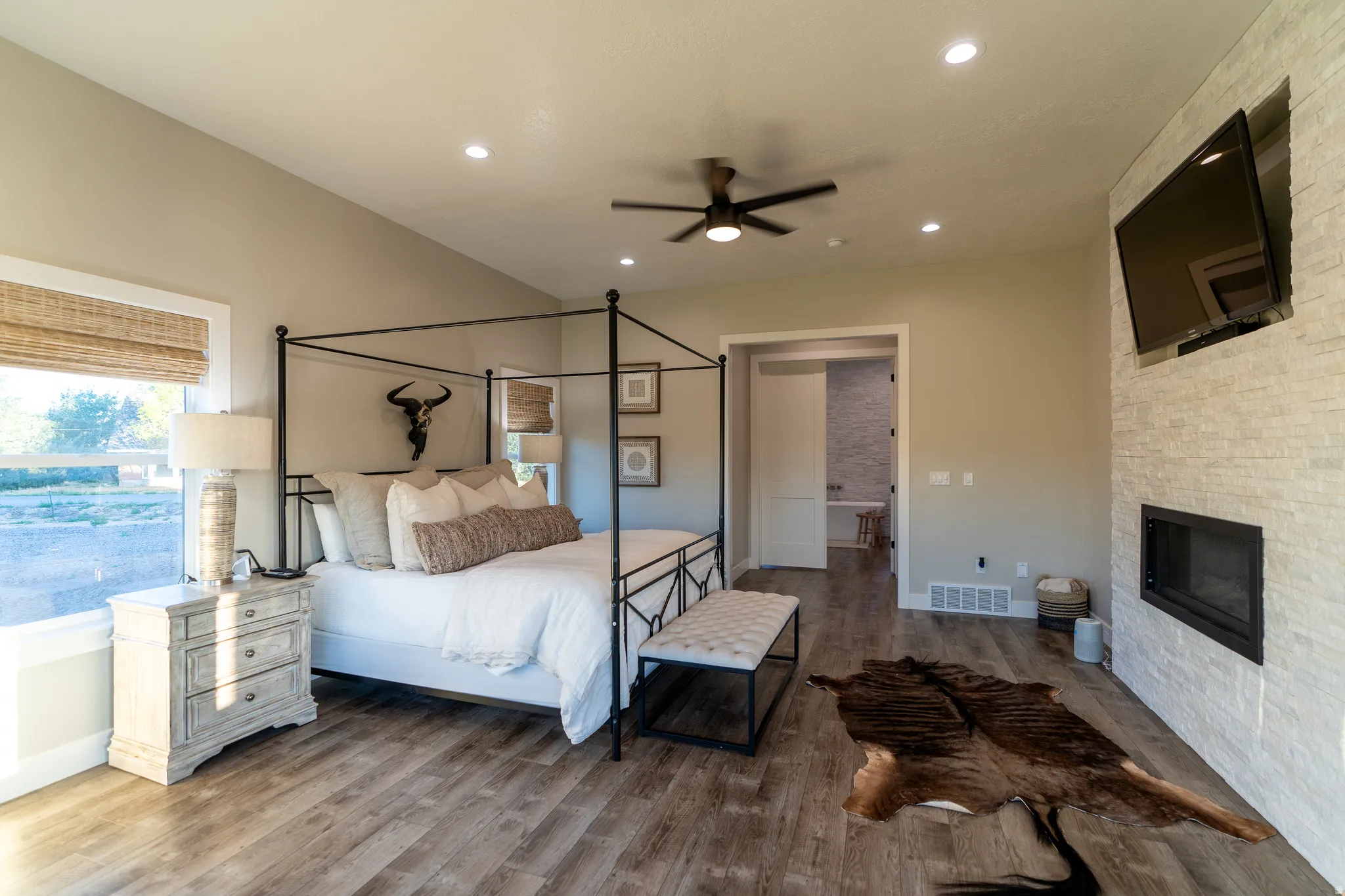 Spacious room featuring wood-finish flooring, a contemporary fireplace with a stacked stone surround, and recessed lighting