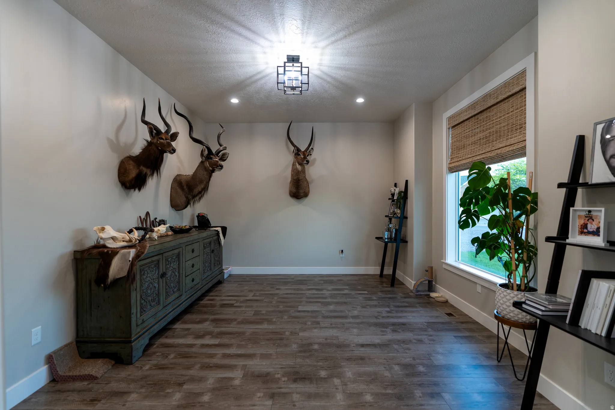 Spacious room featuring wood-finish flooring, recessed lighting, and a modern ceiling light fixture
