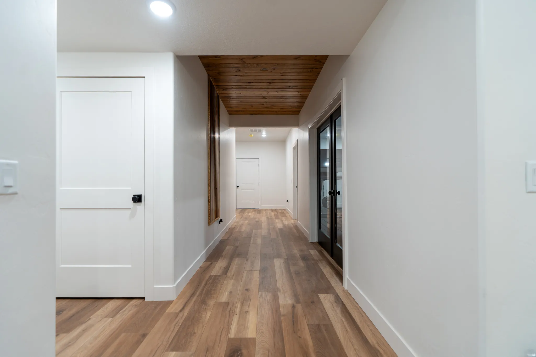 Hallway featuring wood-finish flooring, recessed lighting, white walls, and a wood plank ceiling detail