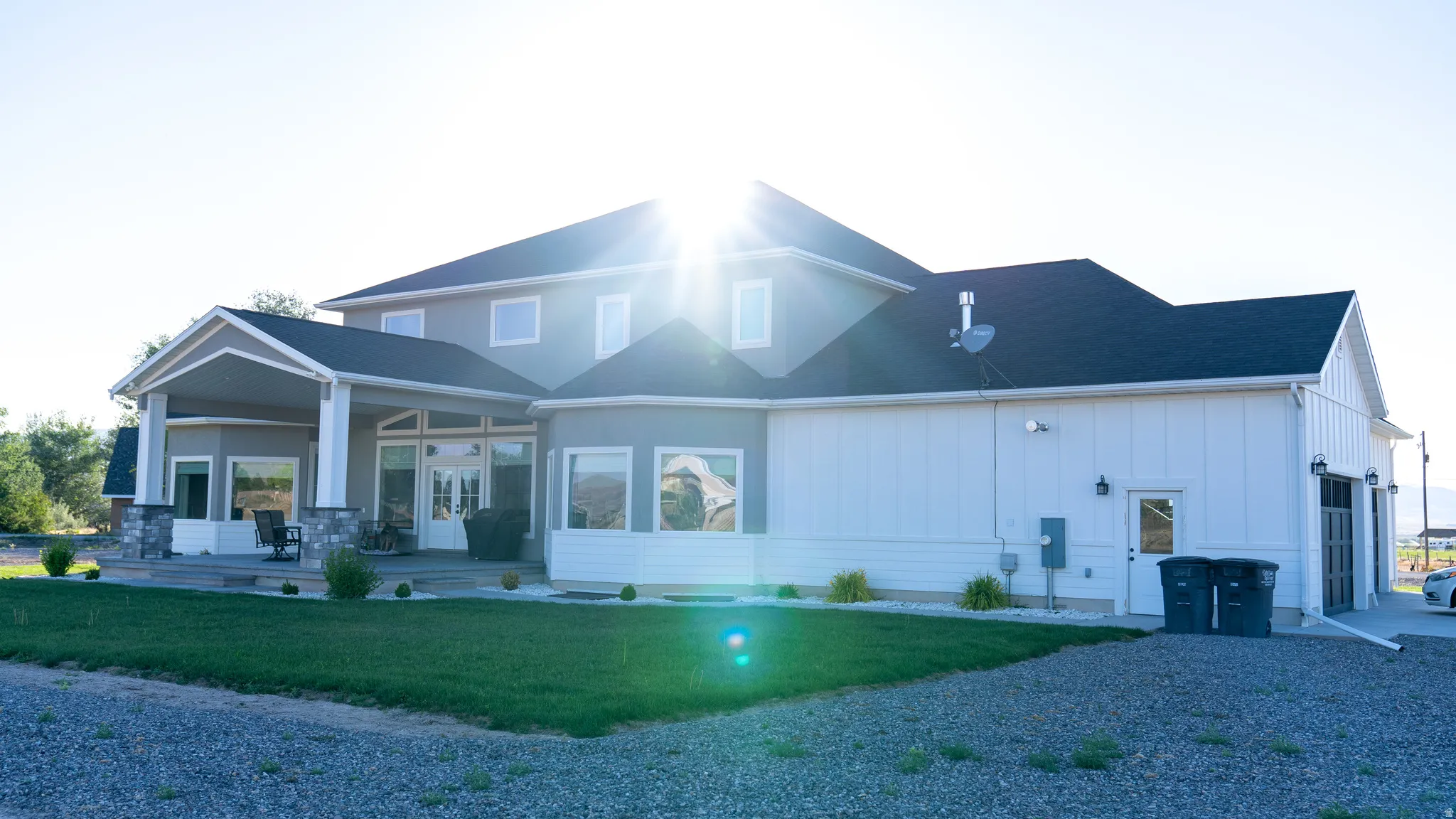 Two-story residence featuring a covered patio, extensive window placements, and an attached garage structure with a multi-pane overhead door