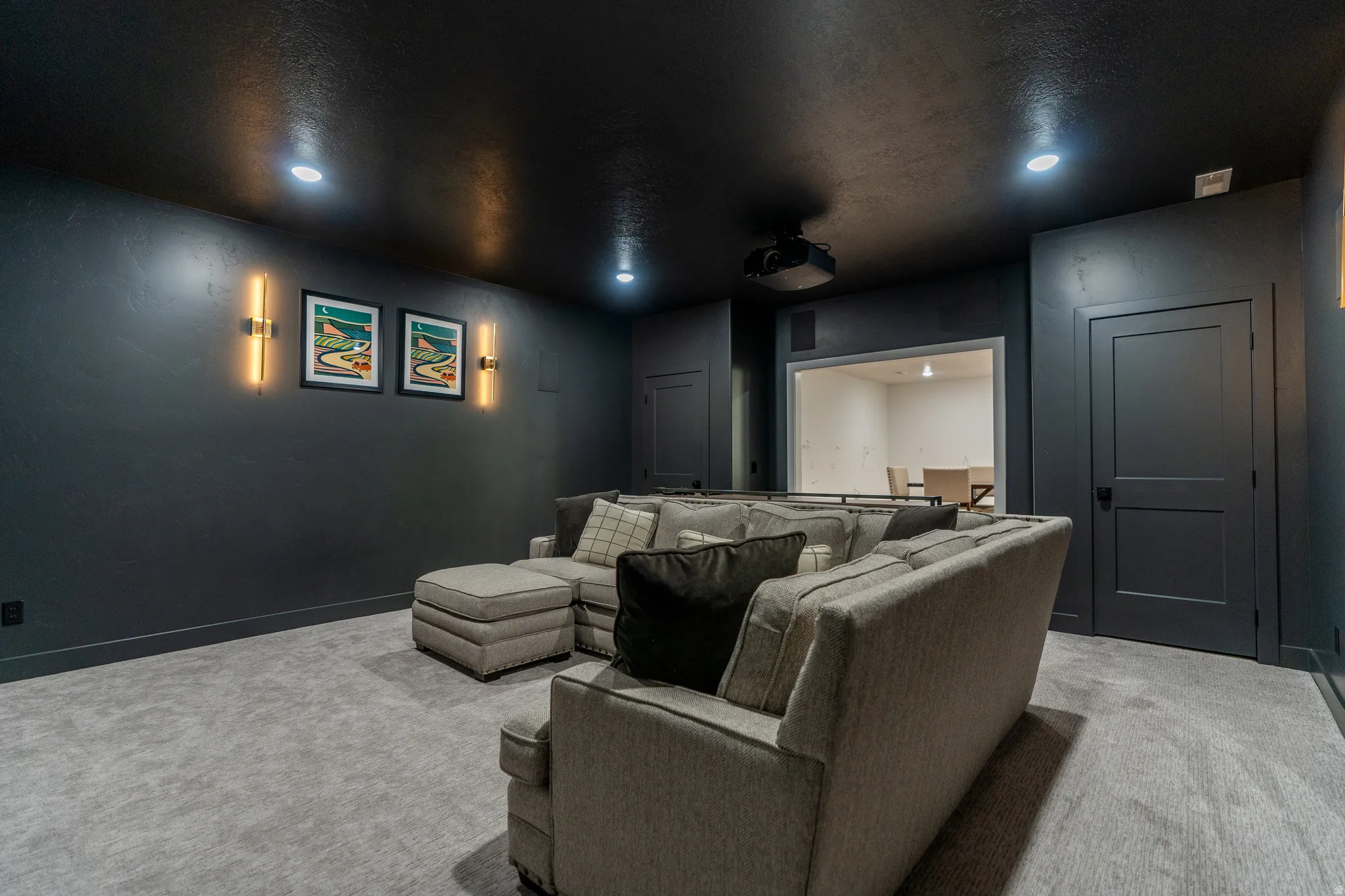 Dedicated entertainment space featuring dark walls, recessed lighting, and a mounted projector