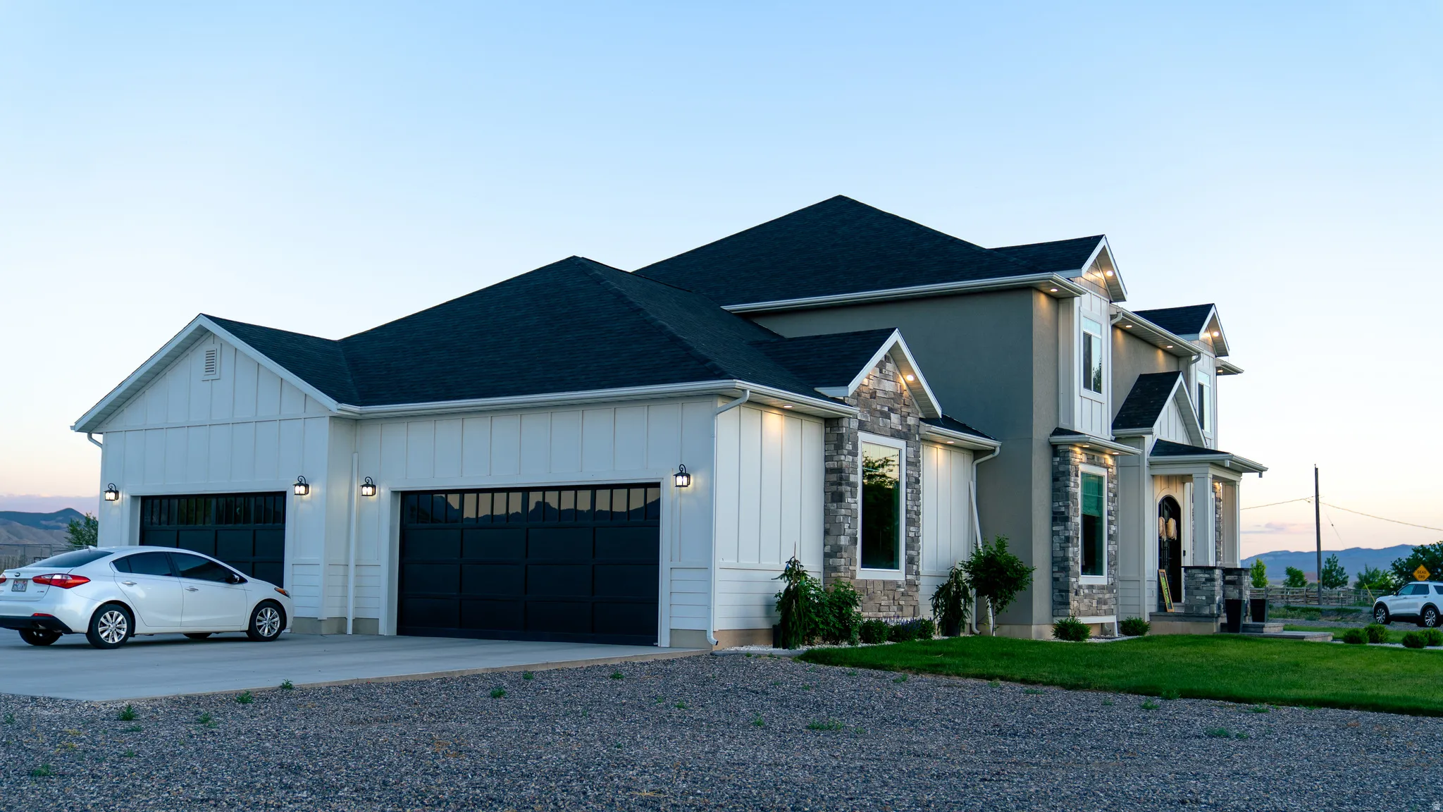 Modern farmhouse-style exterior featuring board and batten siding, stone veneer accents, multi-pane garage doors, and a covered entry porch