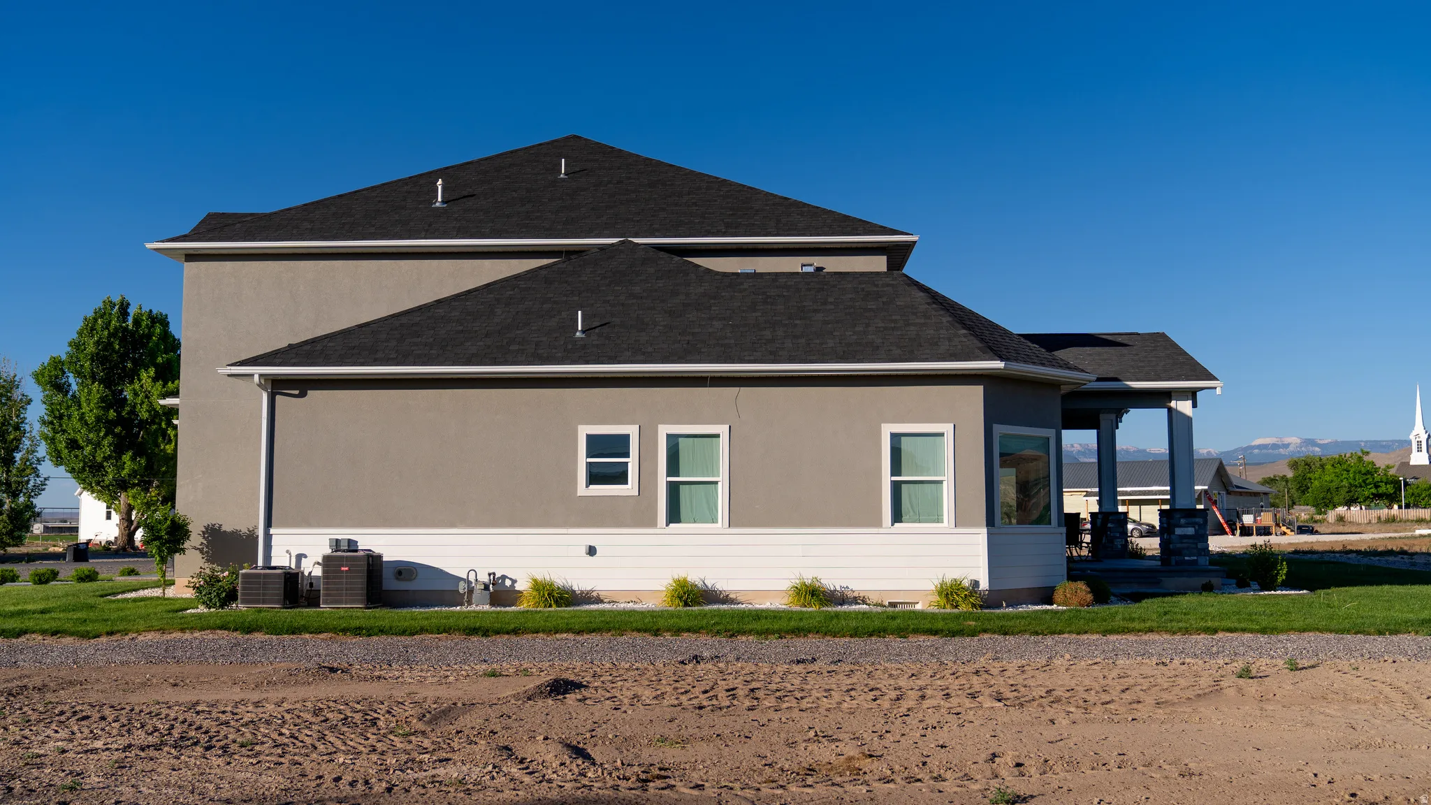 Modern stucco exterior with dark shingle roofing
