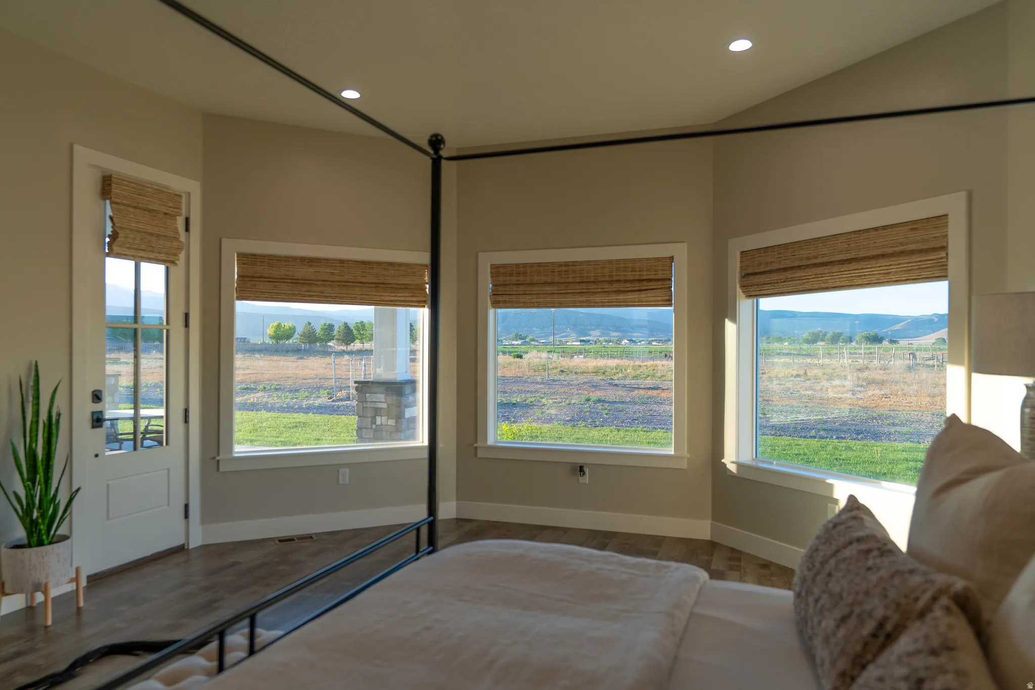 Room featuring a glass-paneled door, multiple large windows with woven blinds, and wood-finish flooring
