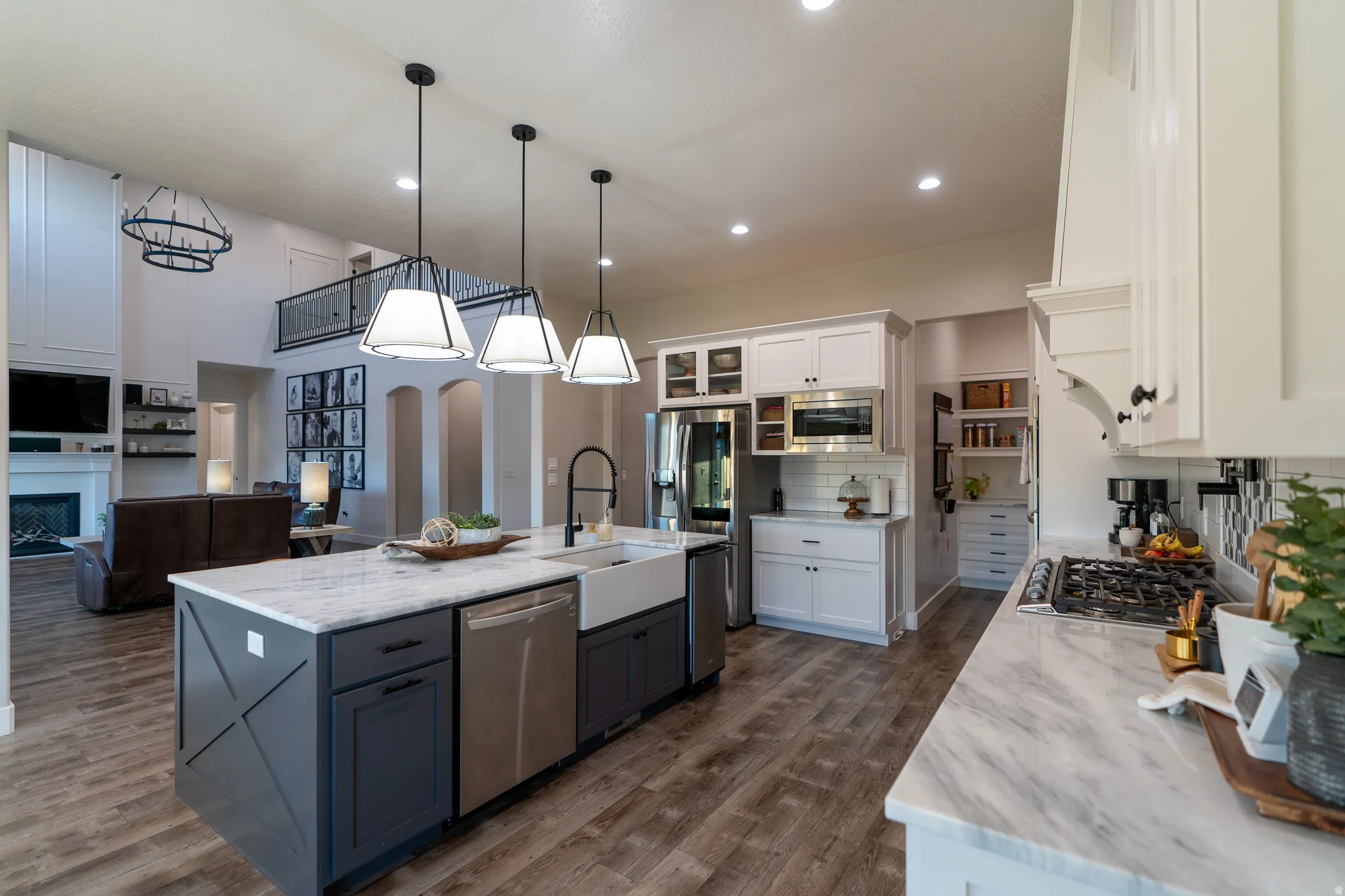Gourmet kitchen featuring a large central island with an integrated farmhouse sink, white countertops, and wood-finish flooring