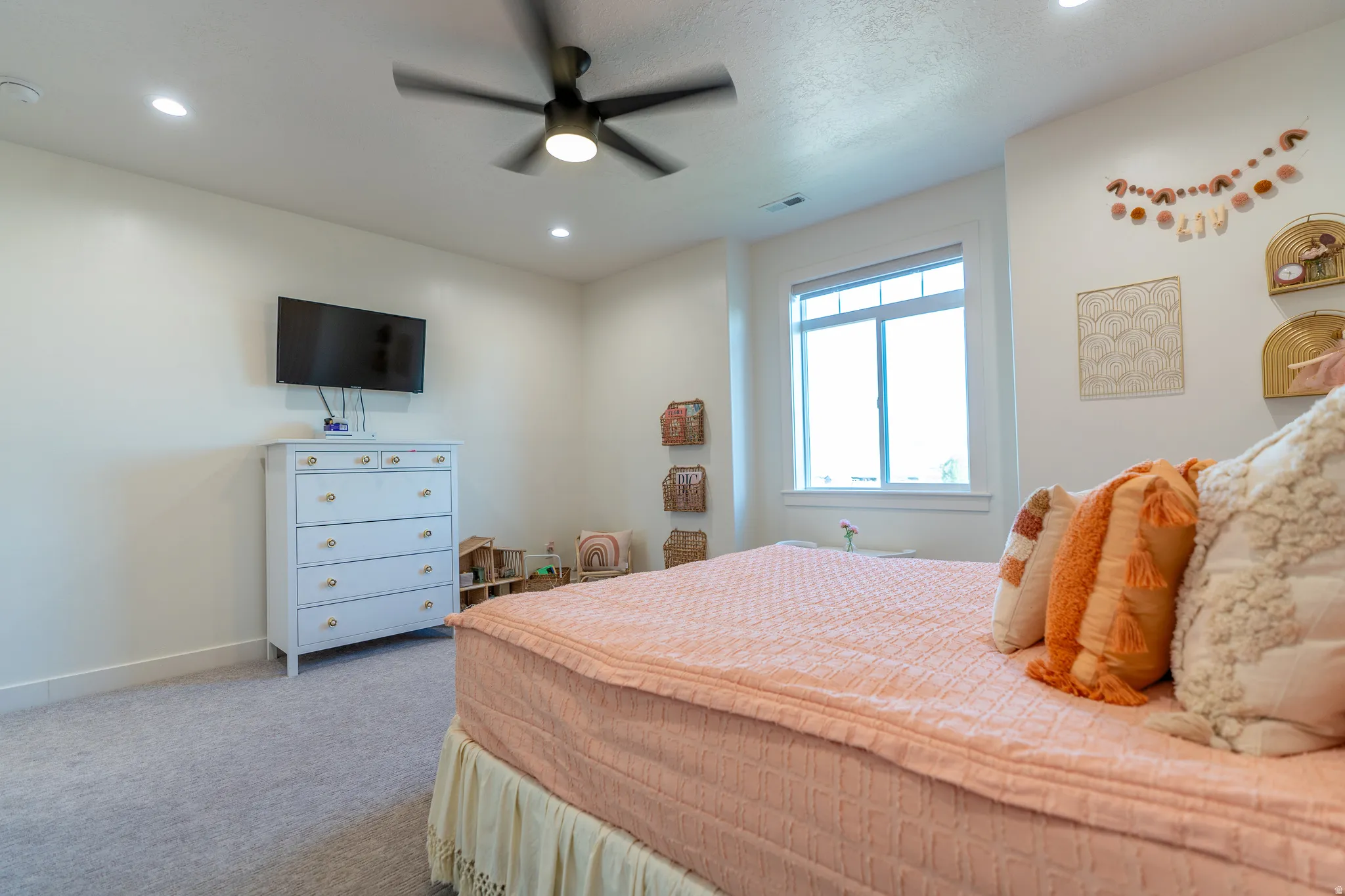 Spacious room featuring light gray carpet flooring, recessed lighting, and a prominent window with white trim