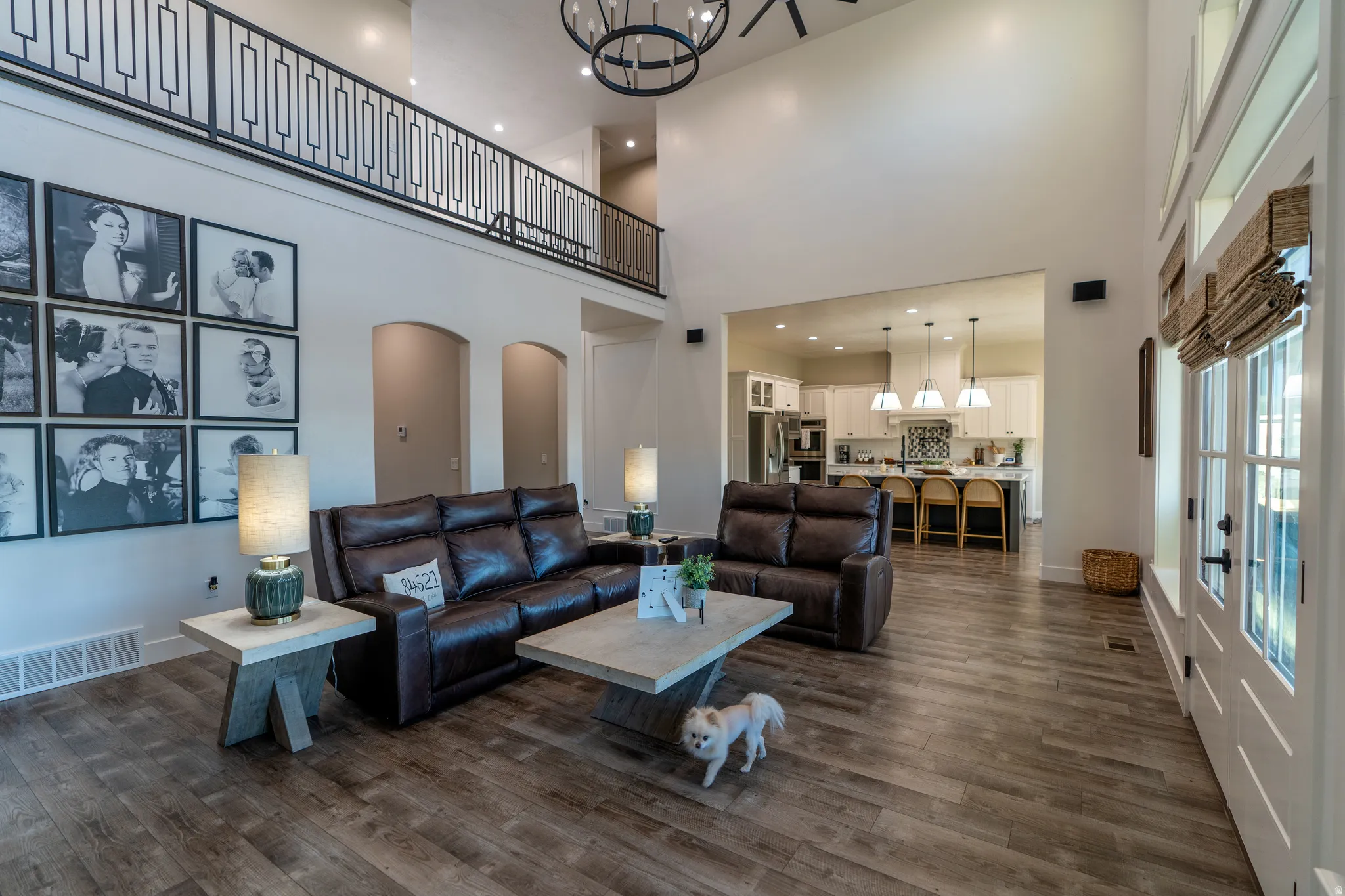 Great room featuring soaring ceilings, wood-finish flooring, and a second-story balcony with decorative railing
