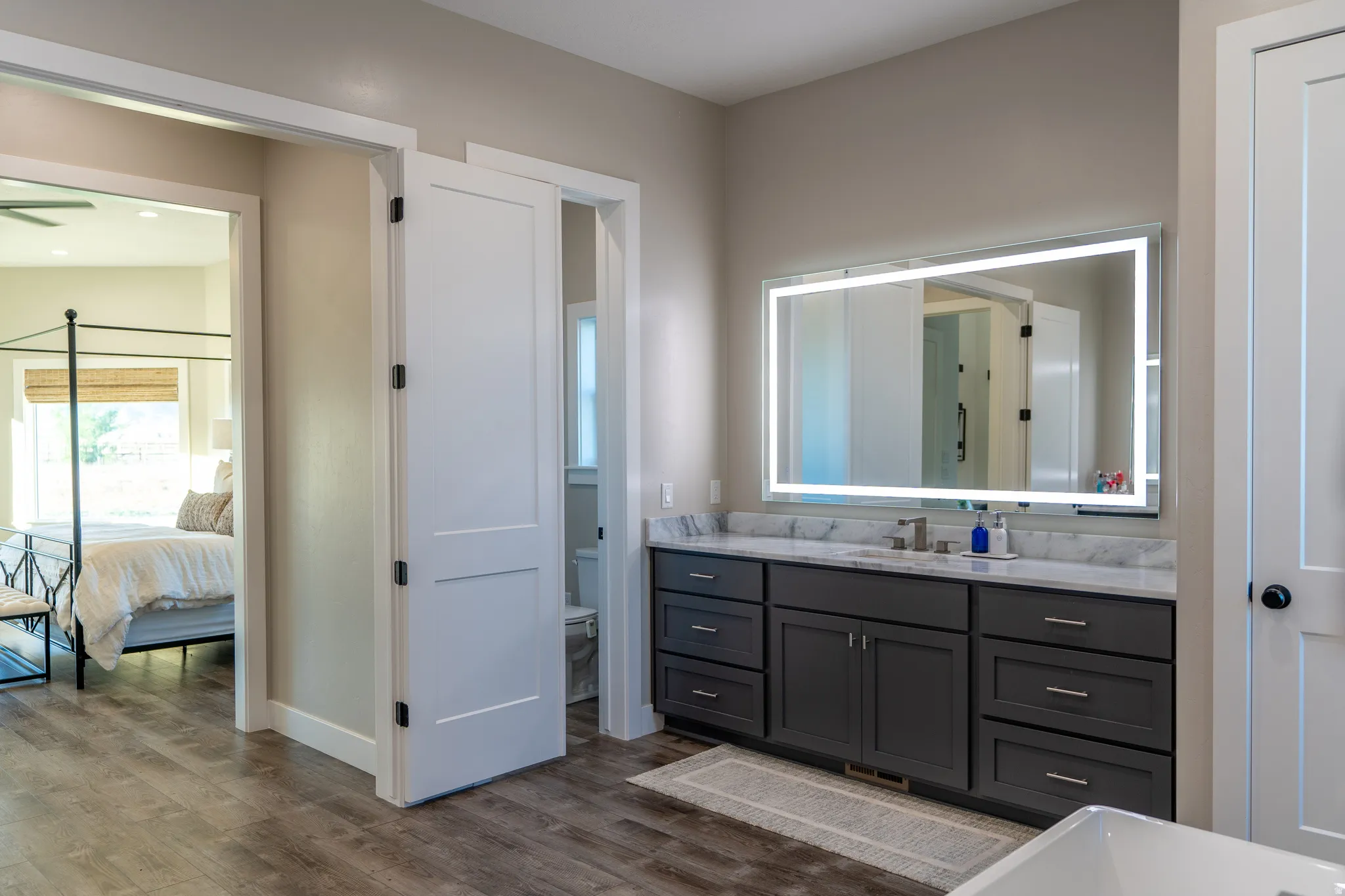 Bathroom vanity with a white countertop, undermount sink, and illuminated mirror