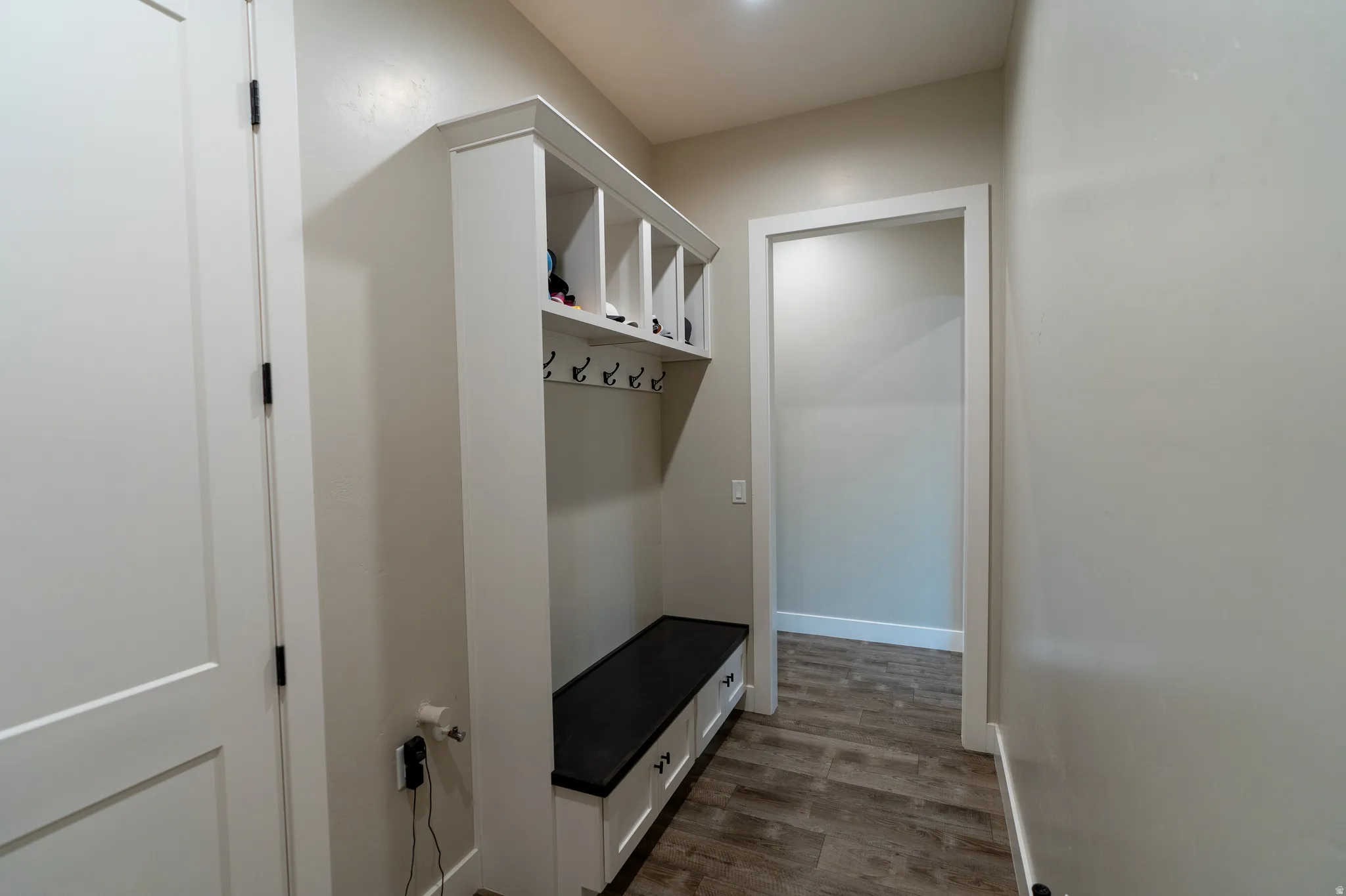Built-in mudroom bench with storage cubbies and coat hooks, complemented by wood-finish flooring