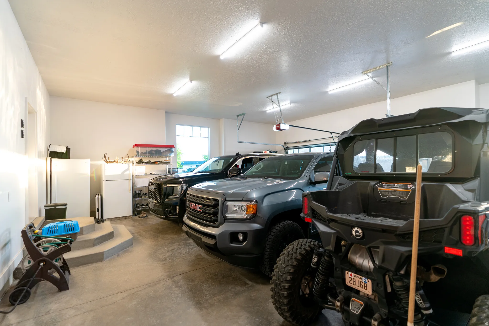 Spacious garage featuring a concrete floor, multiple fluorescent light fixtures, and a white ceiling