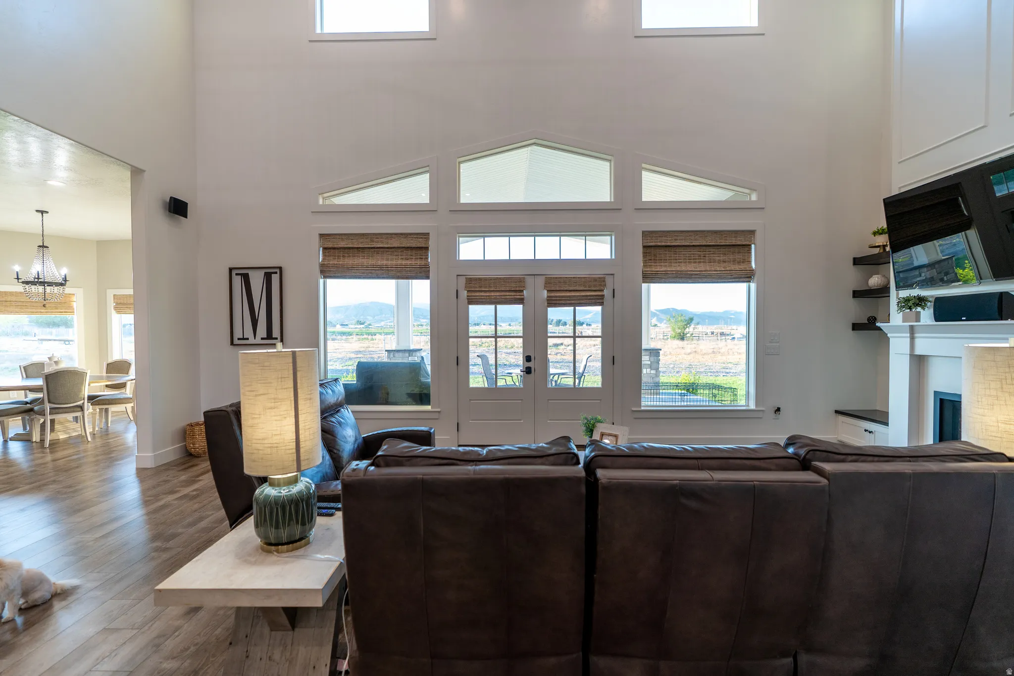 Vaulted ceiling living area featuring wood-finish flooring, a white mantel fireplace, built-in shelving, and French doors