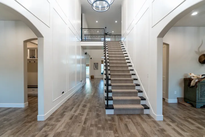 Two-story foyer featuring a grand staircase with carpeted treads and a wrought iron railing