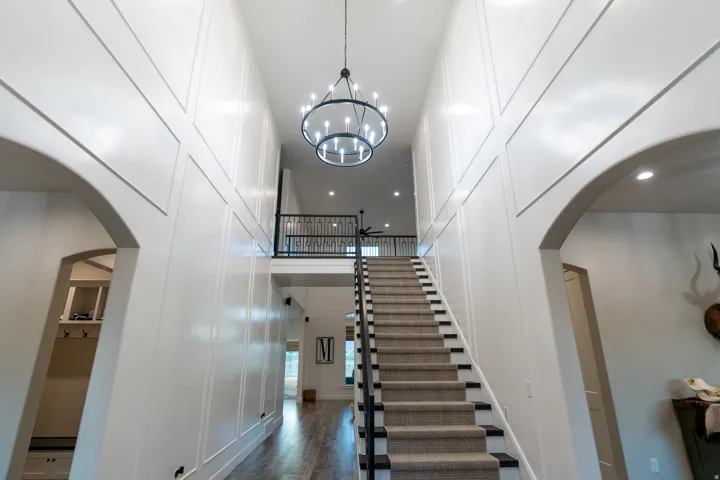 Two-story foyer featuring a grand staircase with carpeted treads and dark wood risers