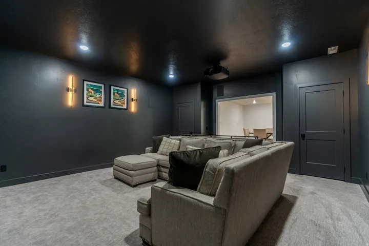 Dedicated entertainment space featuring dark walls, recessed lighting, and a mounted projector