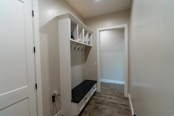 Built-in mudroom bench with storage cubbies and coat hooks, complemented by wood-finish flooring